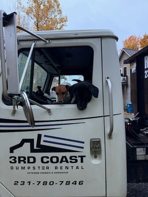 Dog leaning out of a white 3rd Coast Dumpster Rental truck window