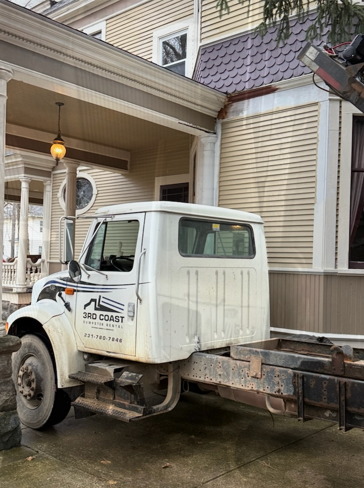 White utility truck parked beside a beige house under a covered porch.