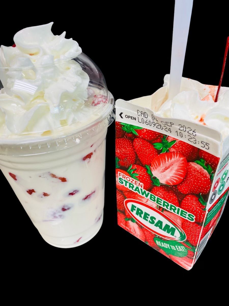 A cup of strawberry milkshake next to a carton of strawberry juice
