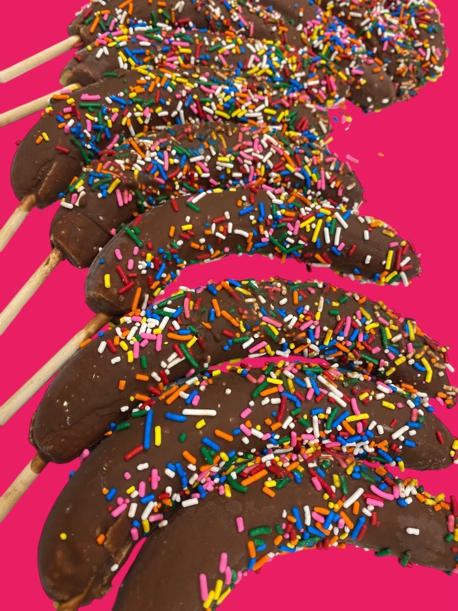 Chocolate covered bananas with sprinkles on a pink background