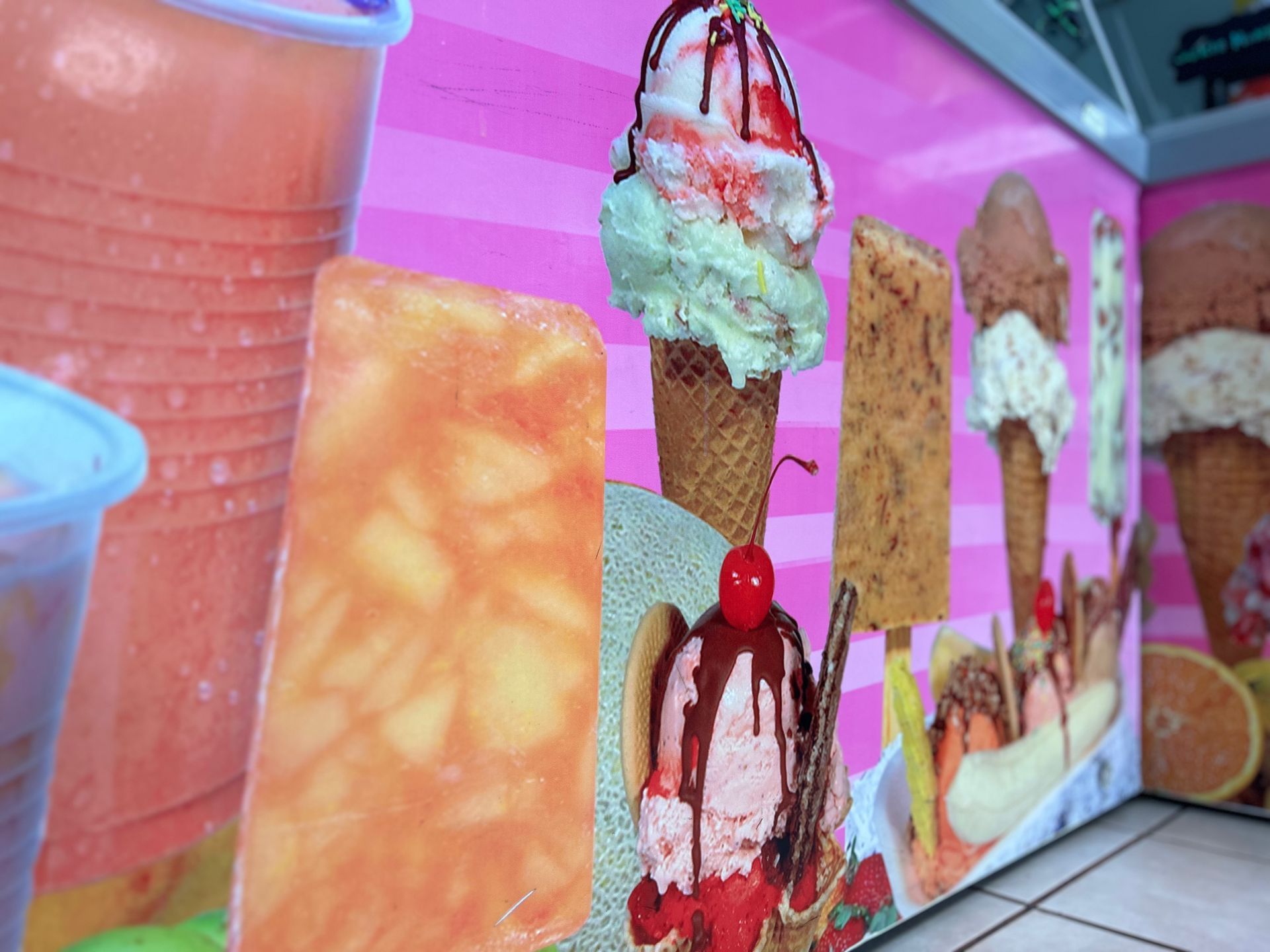 A pink wall with ice cream cones and juices on it
