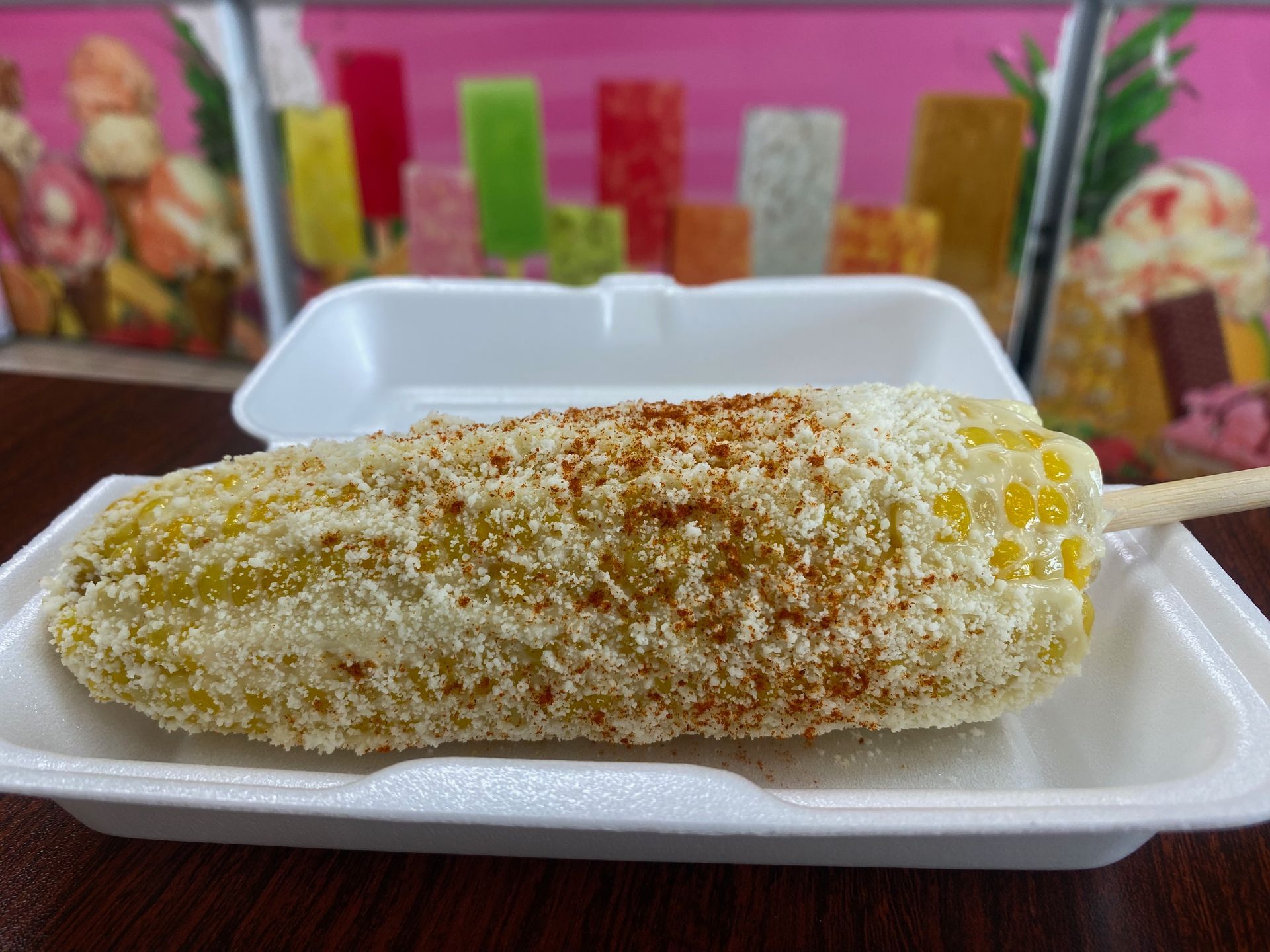 A close up of a corn on the cob in a styrofoam container on a table.