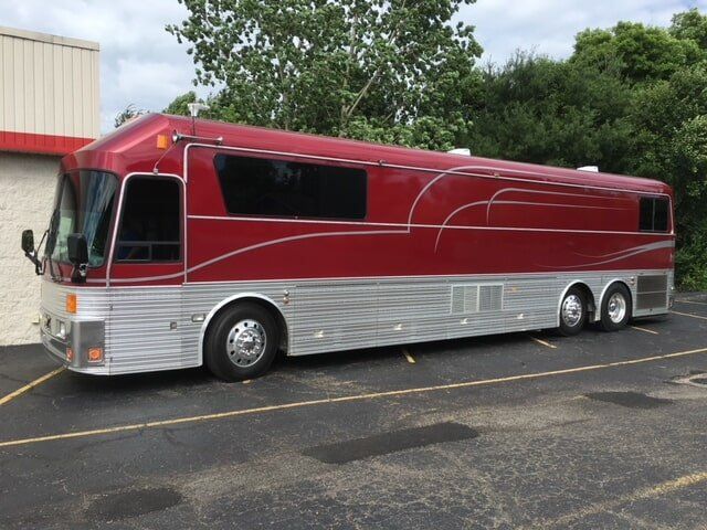 A red and silver bus is parked in a parking lot