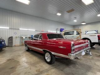 A red car is parked in a garage next to a white truck.