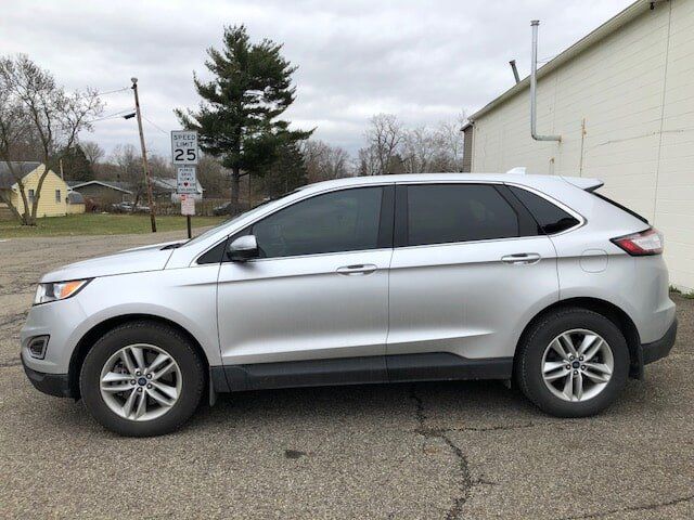 A silver ford edge is parked in front of a building.
