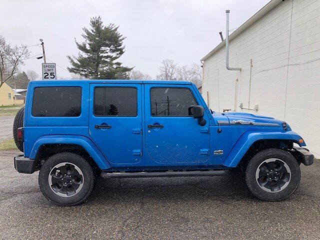 A blue jeep is parked in front of a white building.