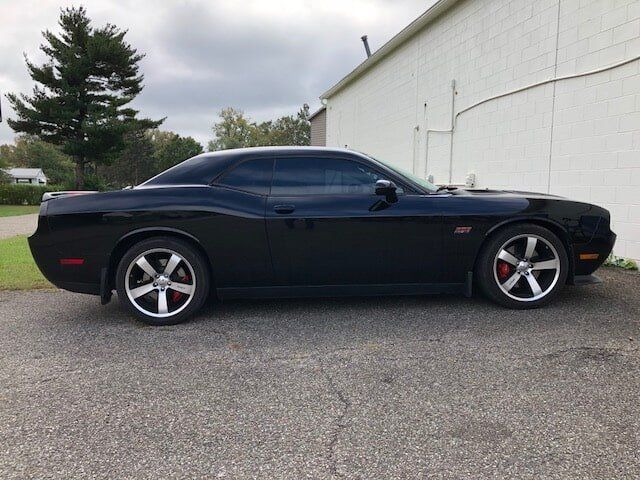 A black dodge challenger is parked in front of a white building.