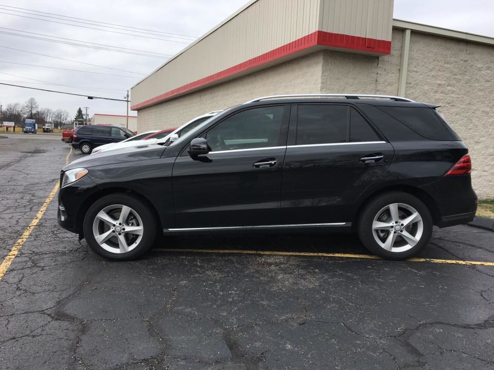 A black suv is parked in a parking lot in front of a building.