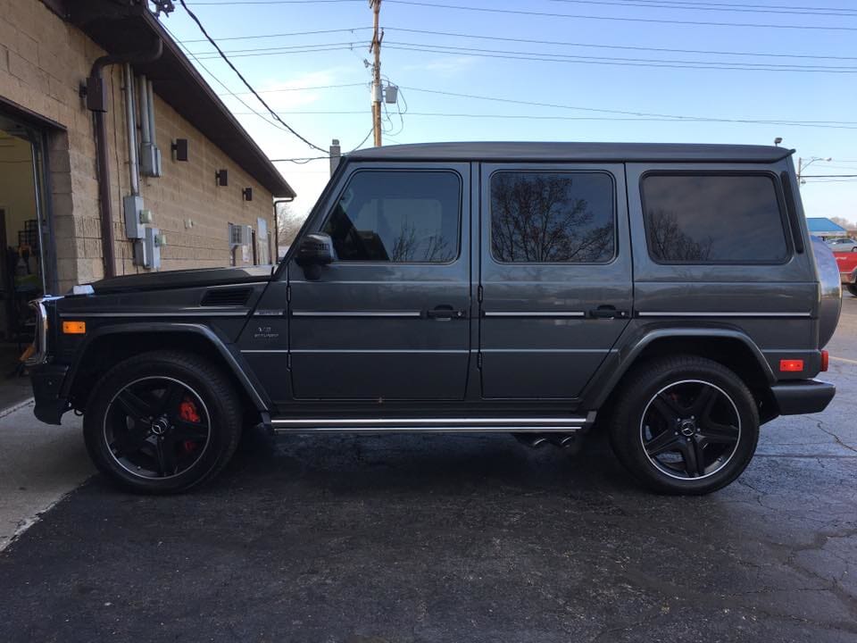 A black mercedes benz g63 is parked in front of a garage.