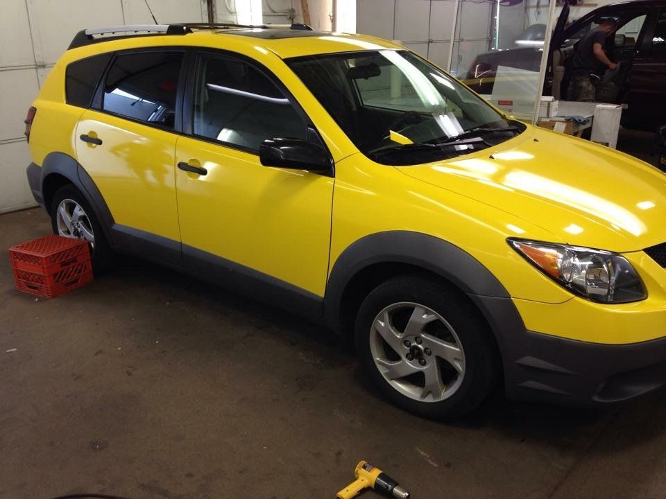 A bright yellow car is parked in a garage