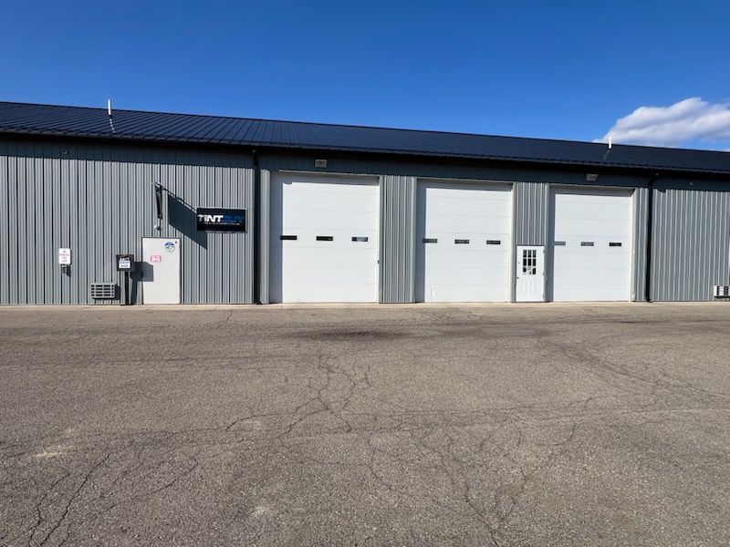 A gray building with white garage doors and a sign that says twp