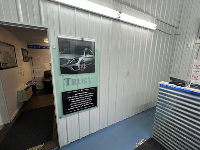 A white wall with a picture of a car on it and a sign that says trust.