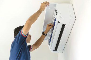 Technician repairing a wall-mounted air conditioner with tools