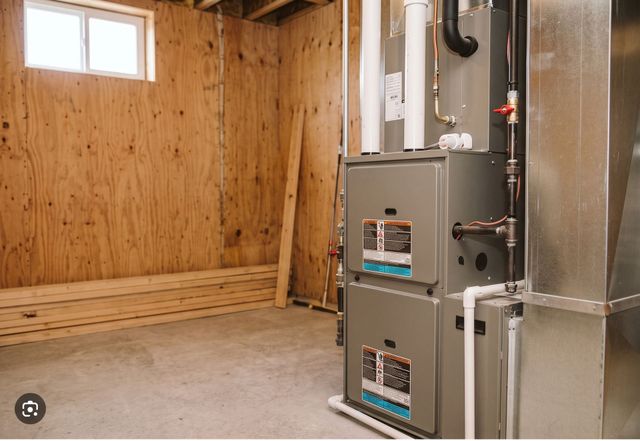 Empty utility room with wood-paneled walls, small window, and large gray HVAC/furnace unit.