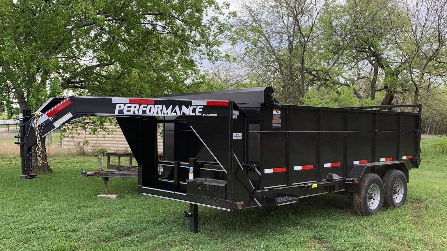 A dump trailer is parked in a grassy field.