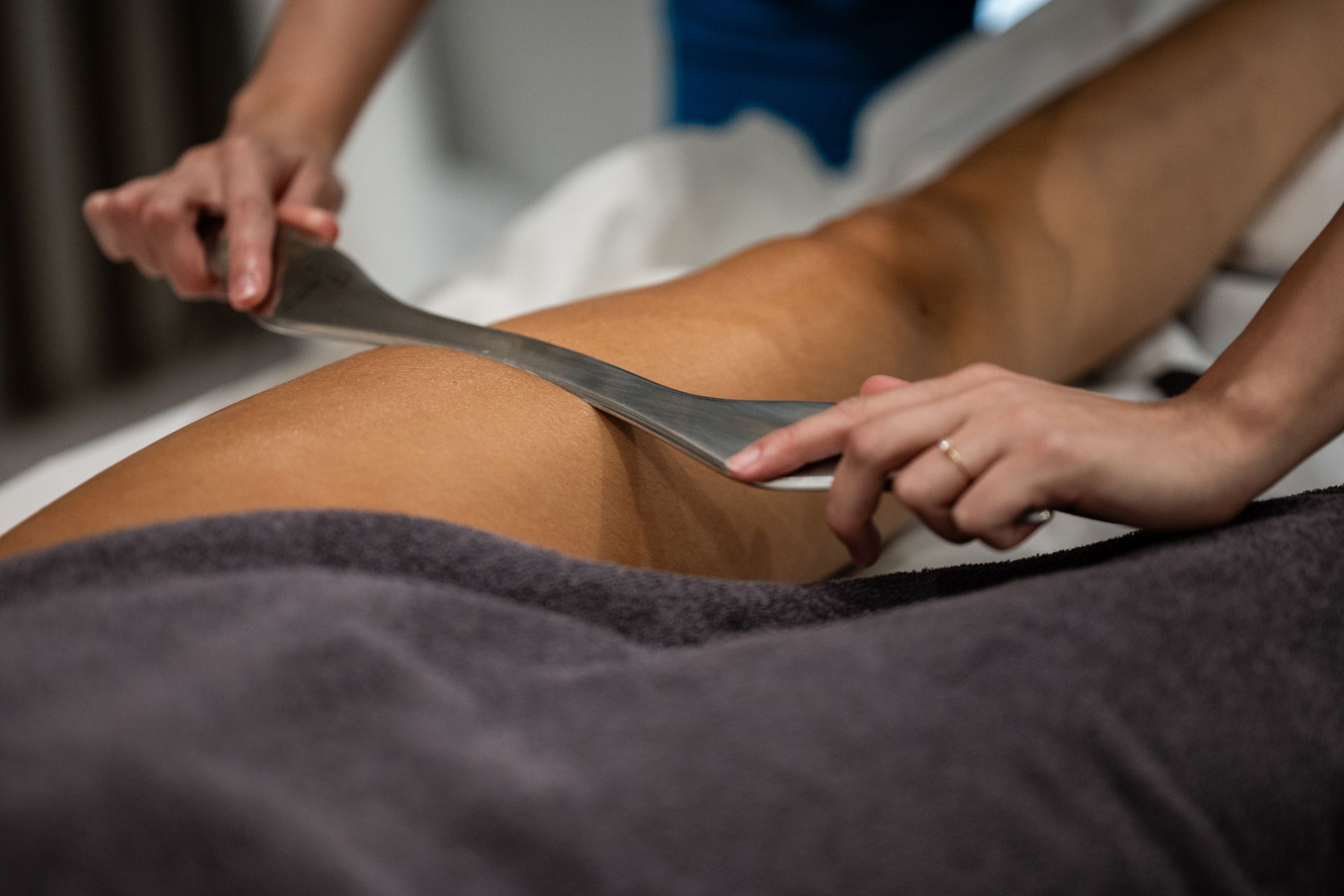 Hands measuring a person’s waist with a tape measure on a massage table