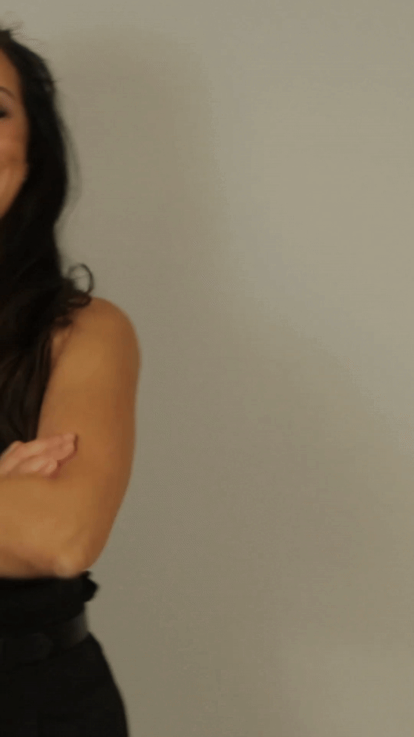 A woman in a black dress is standing with her arms crossed.