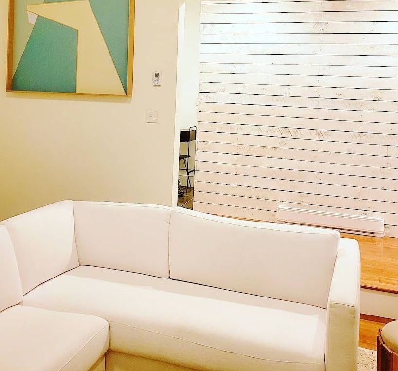 White sectional sofa in living room with art and a shiplap wall.