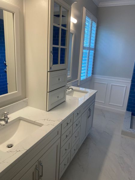 Bathroom with white cabinets, blue tile accents, and a marble countertop.
