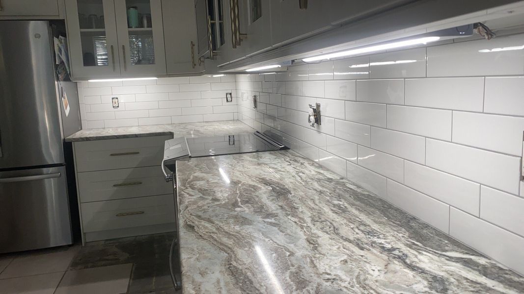 Kitchen remodel: White subway tile backsplash, granite countertops, under-cabinet lighting.
