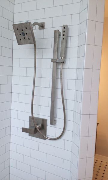 Shower with square showerhead and handheld wand on white subway tile.
