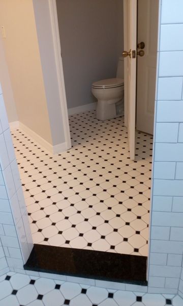 Bathroom doorway, featuring black and white patterned tile flooring. Toilet visible in the background.