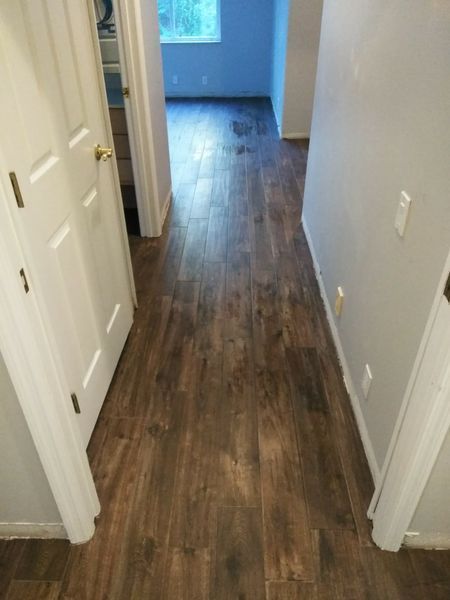 Hallway with dark wood-look flooring, gray walls, and white doors leading to rooms.