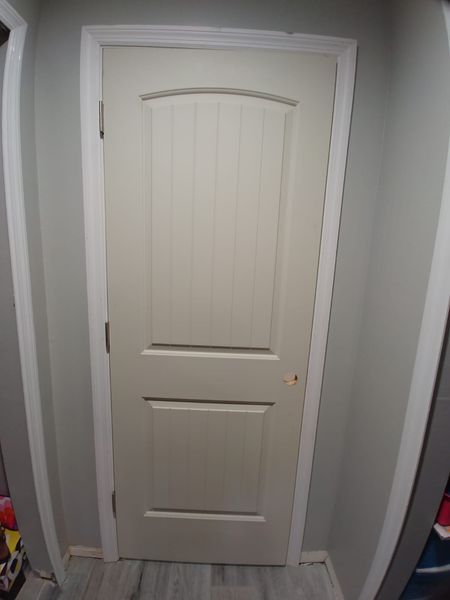 Closed, off-white interior door with white trim set in gray walls.