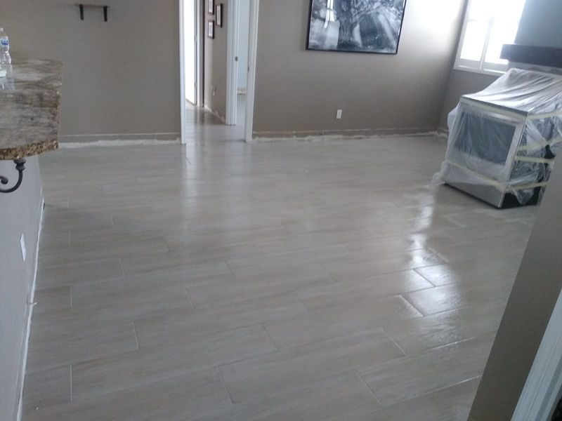 Beige tiled floor in a room, with a covered appliance and neutral walls, doorway visible.