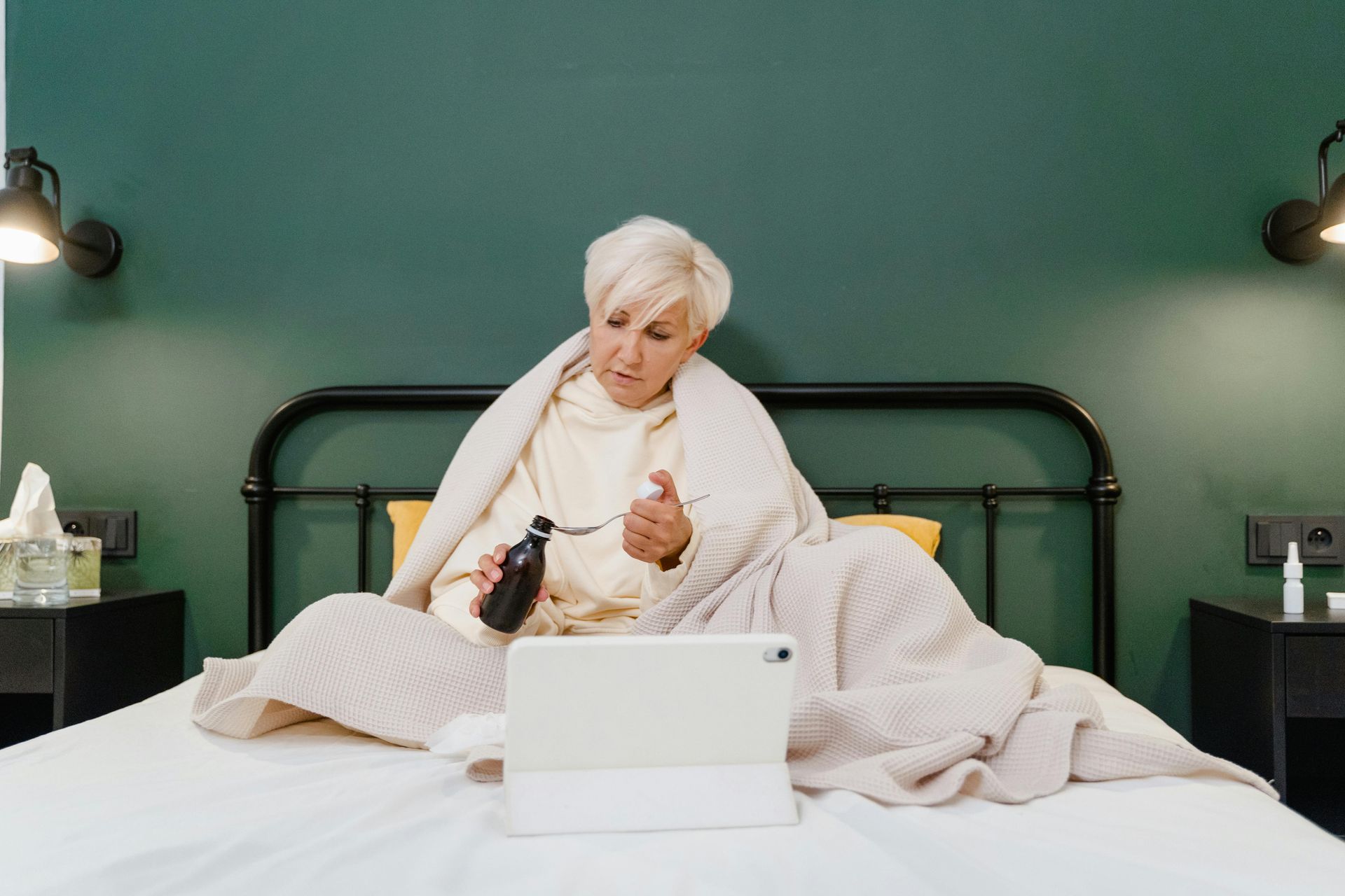 sick elderly woman on bed with tablet An elderly woman is sitting on a bed using a tablet computer.