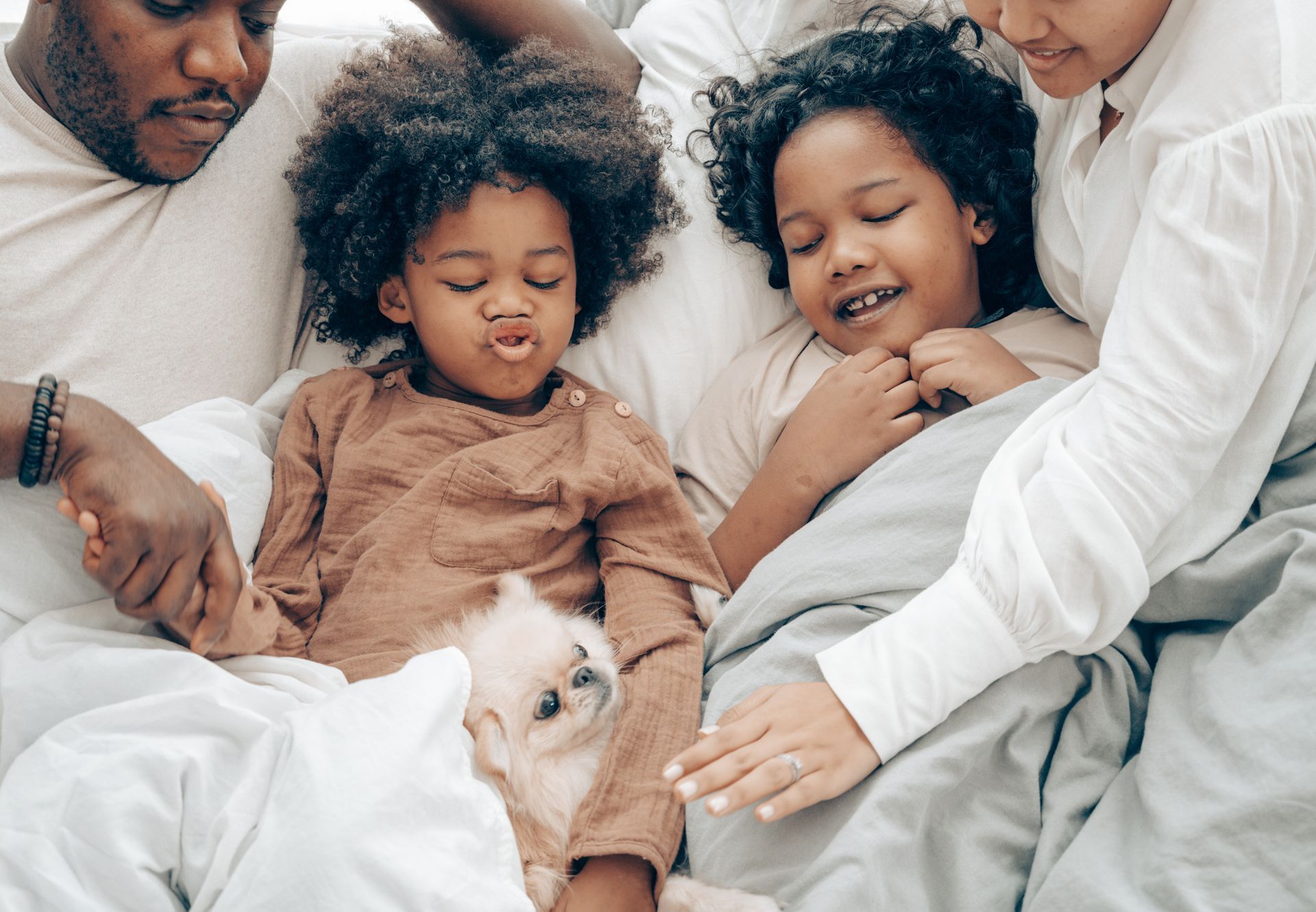 a family is laying in bed with a dog .