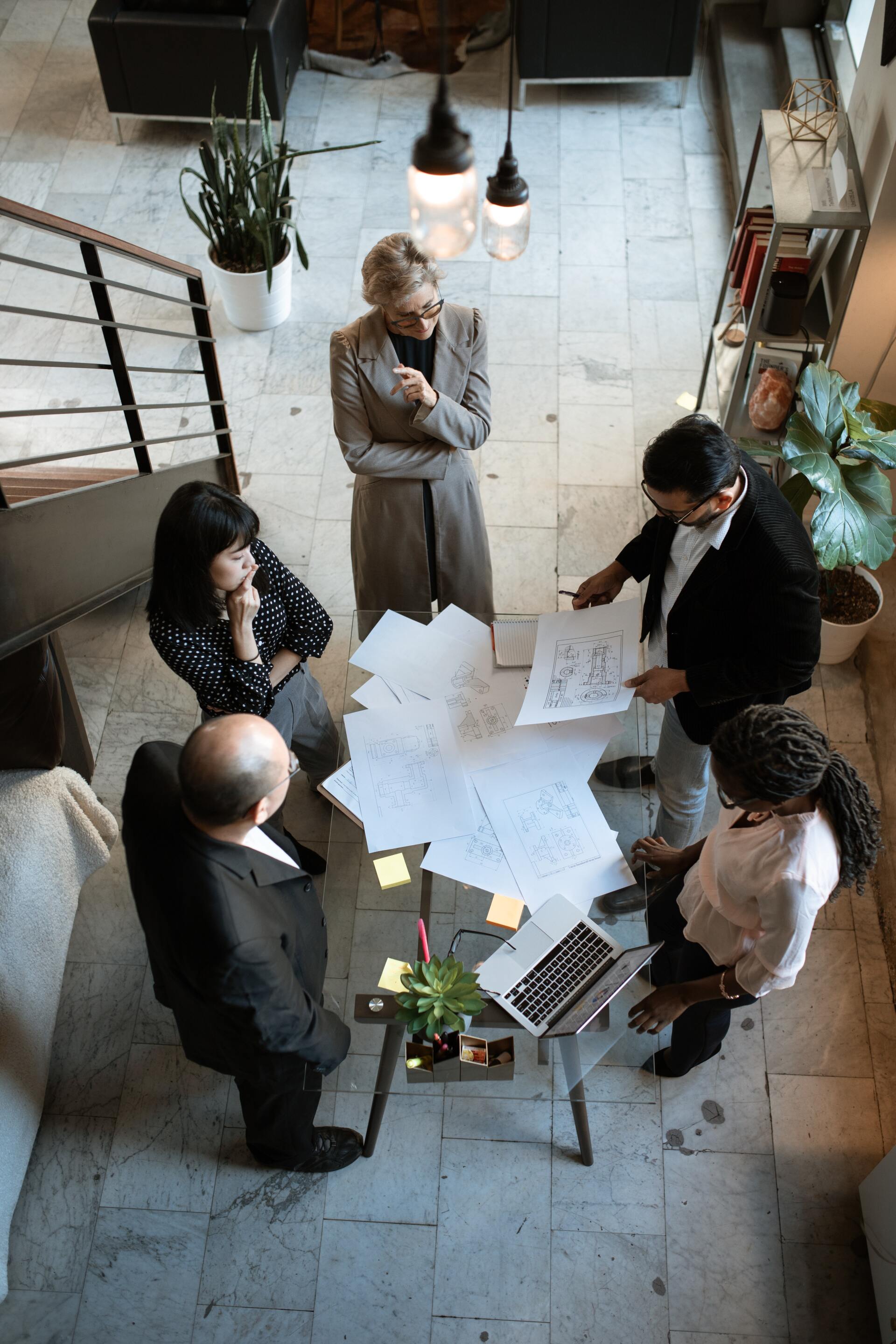 a group of people are sitting around a table with papers and a laptop .