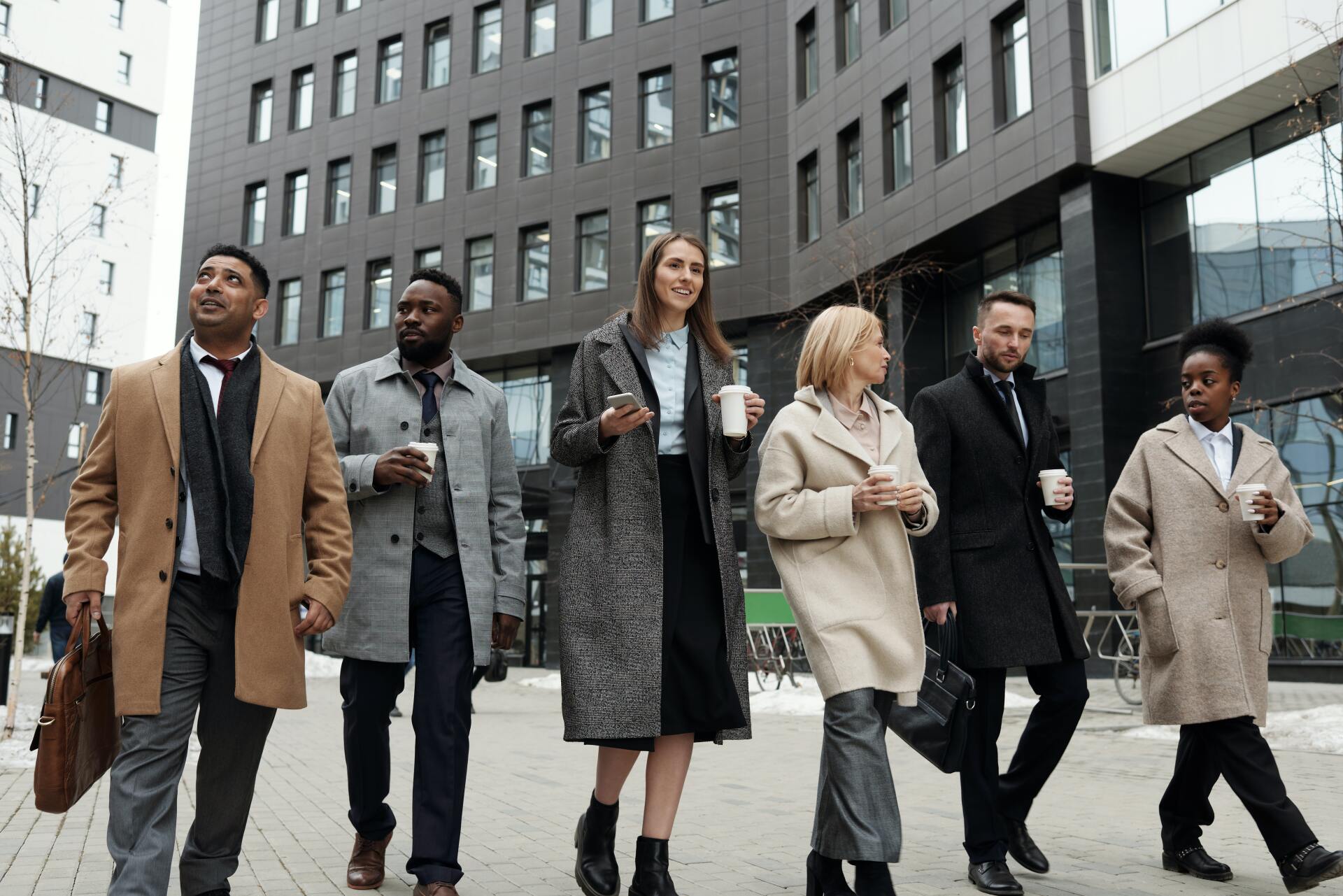 a group of people are walking down a sidewalk in front of a building .