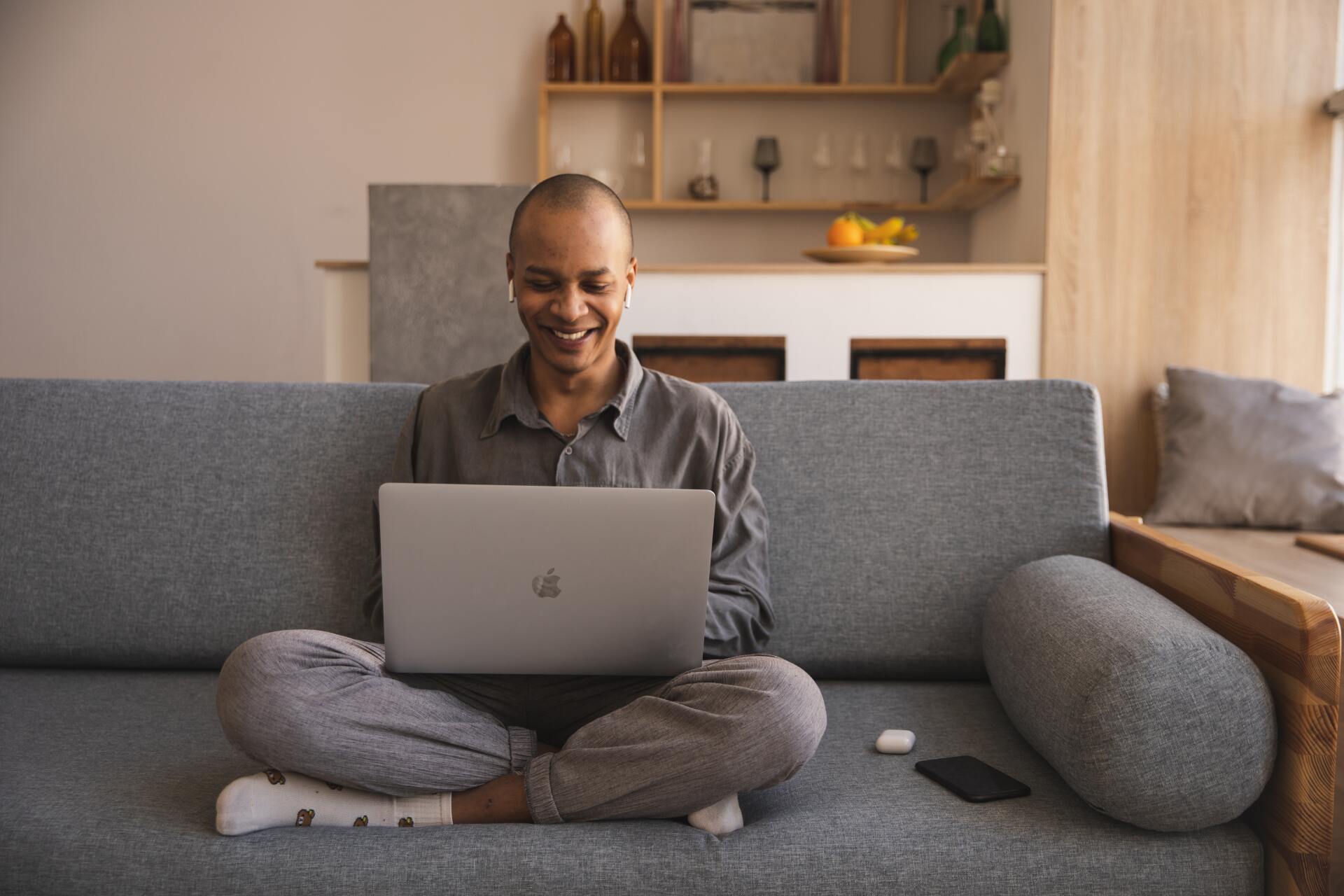 A man is sitting on a couch using a laptop computer.