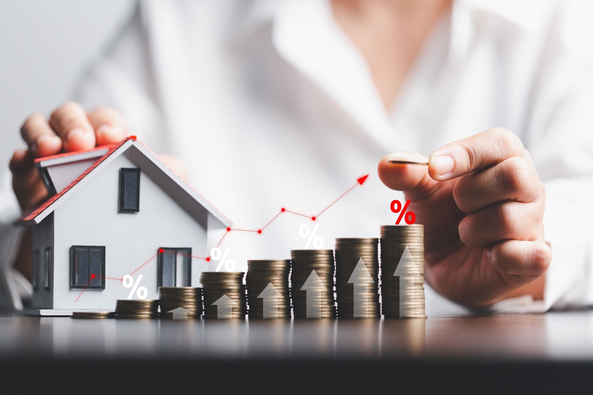 putting a coin on top of a stack of coins next to model house. Illustration of cash value growth A person is putting a coin on top of a stack of coins next to a model house. Illustration of cash value growth