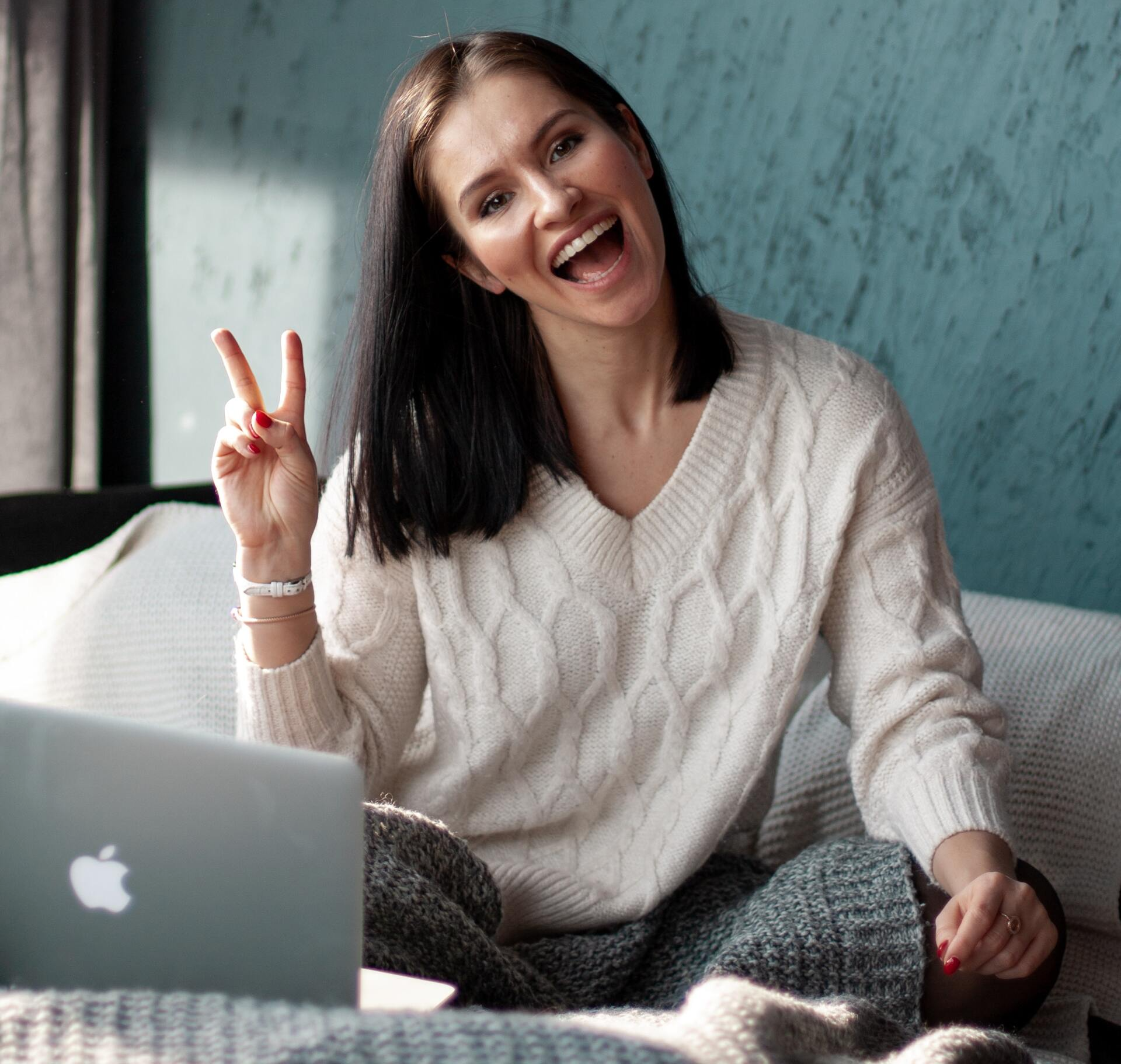 a woman is sitting on a couch in front of an apple laptop