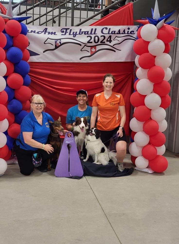 Group of three women and three dogs posing with a
