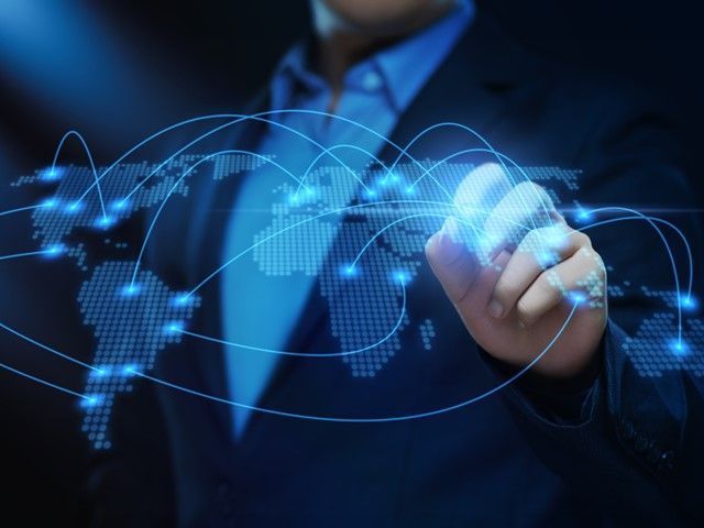 Businessperson touching a glowing digital world map and network lines on a dark blue background