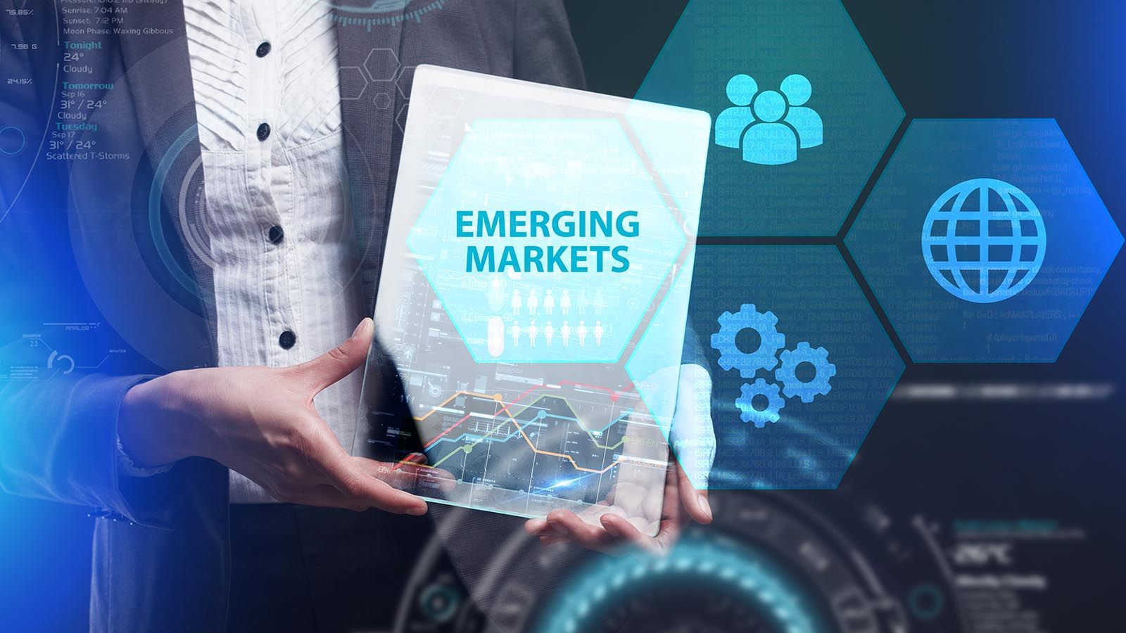 Hand holding a tablet labeled “Emerging Markets” with blue business and tech icons in the background