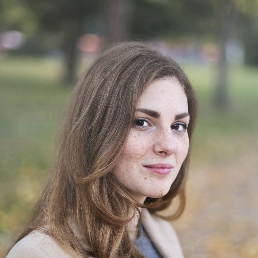 Portrait of a smiling woman outdoors with soft-focus greenery in the background