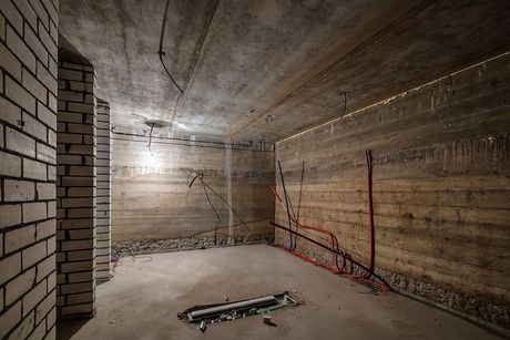 an empty room with a brick wall and electrical wires