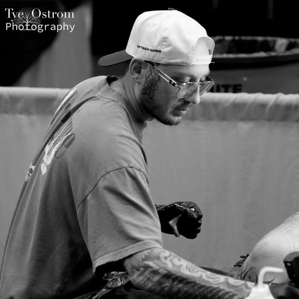 Man wearing a hat and glasses working intently, possibly on a project or task.