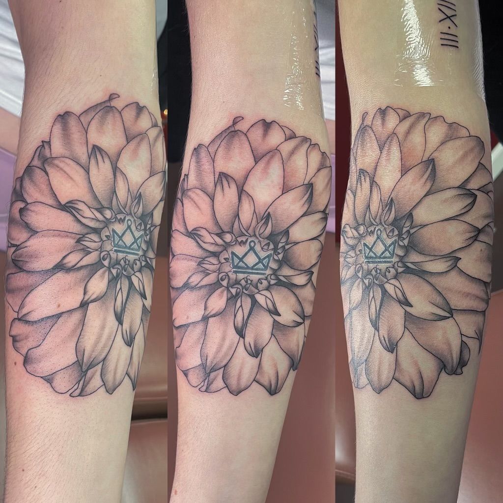 Triptych of flower tattoo on arm, with a crown at the center. Roman numerals are at the top right arm.