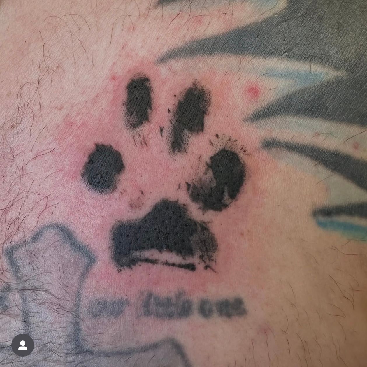 Black paw print tattoo with red skin around it, above the words 