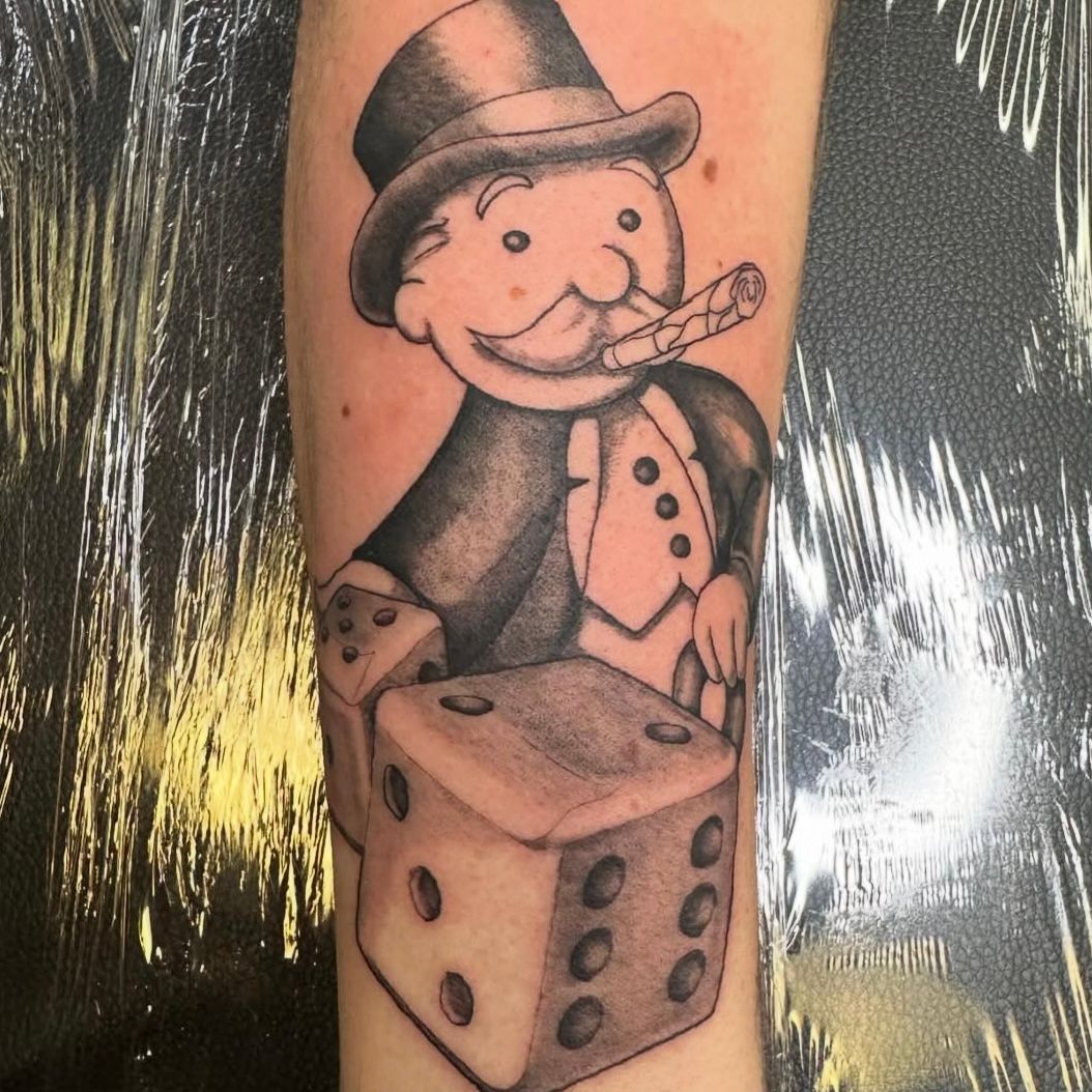 Tattoo of the Monopoly man holding a cigar, standing near dice. Monochrome.
