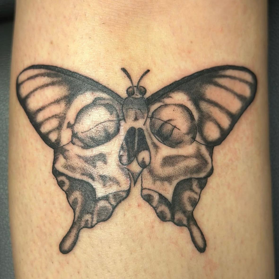 Butterfly tattoo with a skull face design.