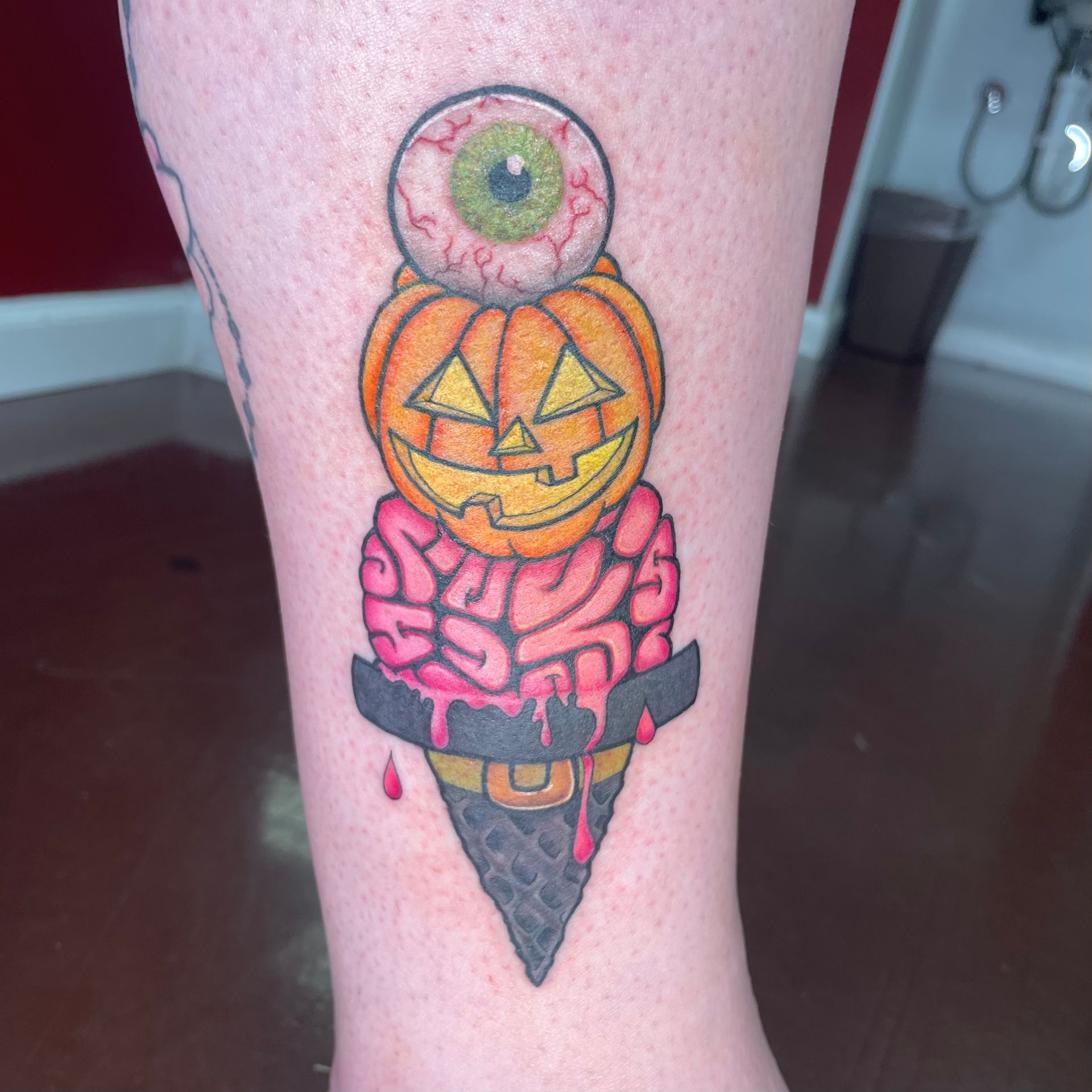 Halloween-themed tattoo of an ice cream cone: eyeball, pumpkin, and brain 