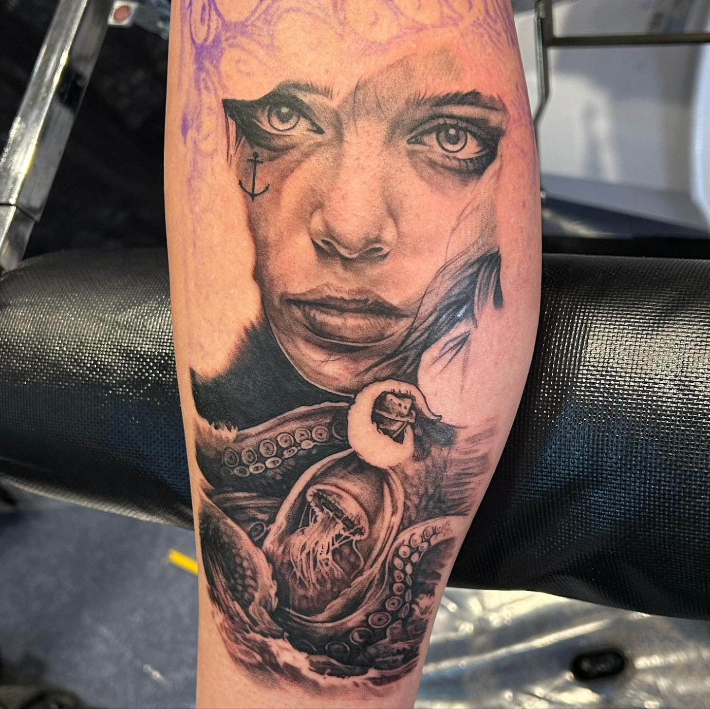 Tattoo of a person's face merging with an octopus. Black ink with detail on a forearm.