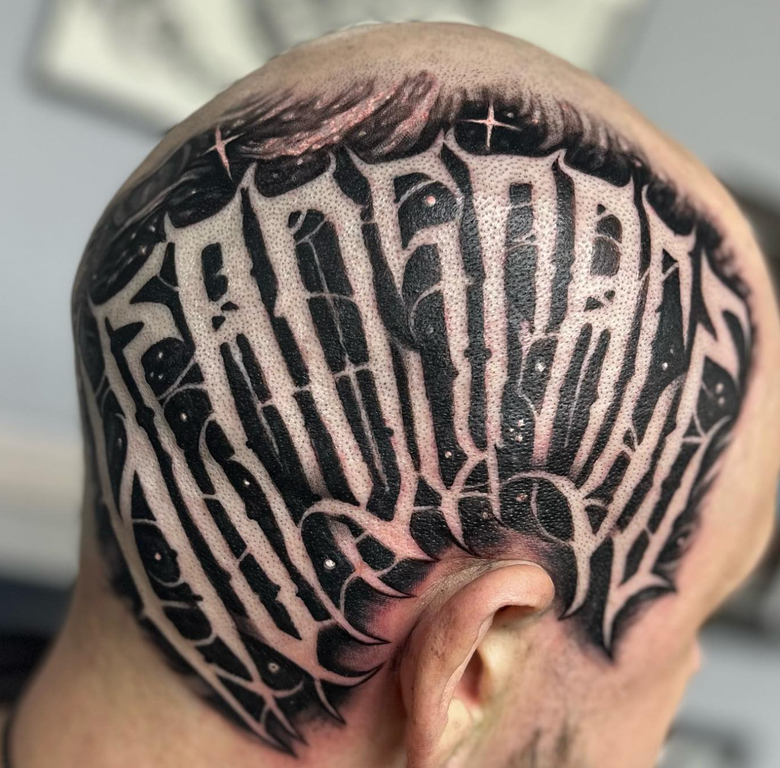 Tattoo on the back of a bald head; black lettering with white outlines; outer space-like background.