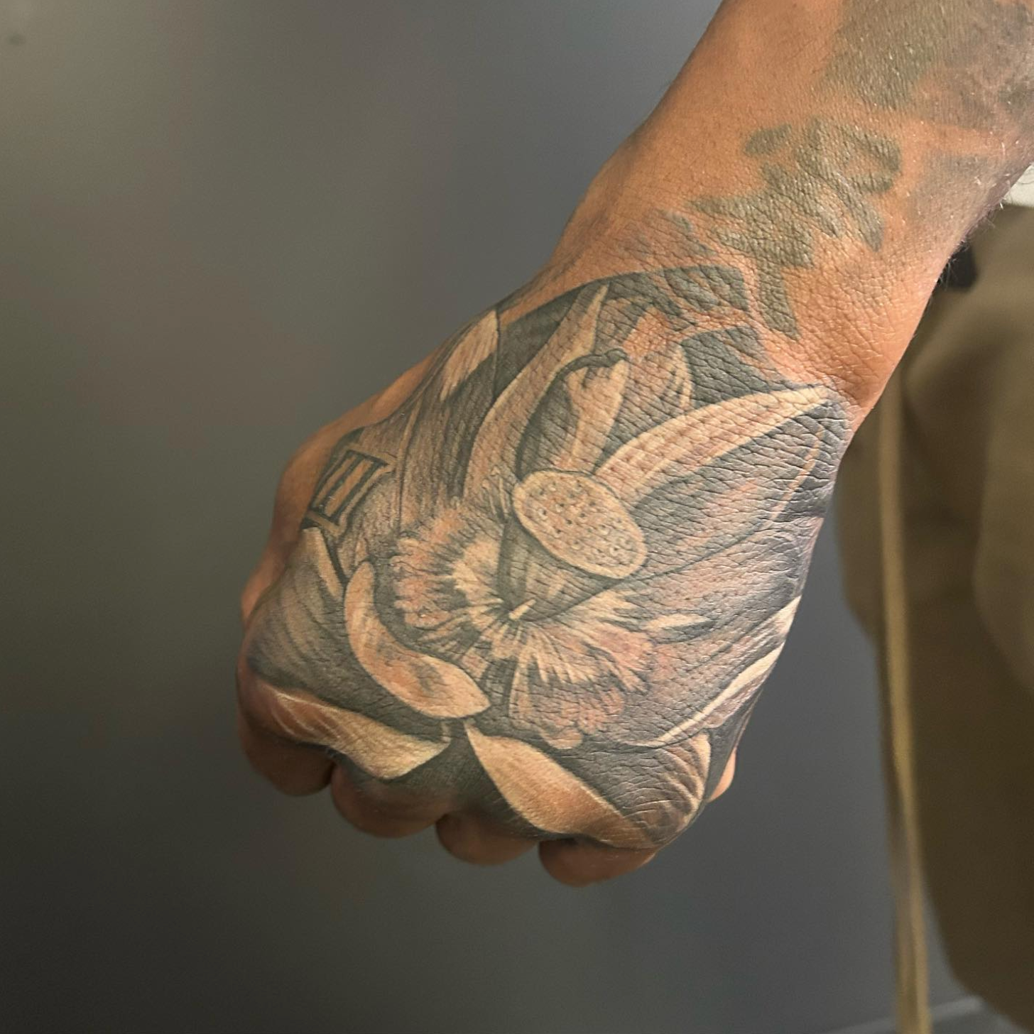 Hand with a detailed black and grey floral tattoo. The person's arm is visible on the right.